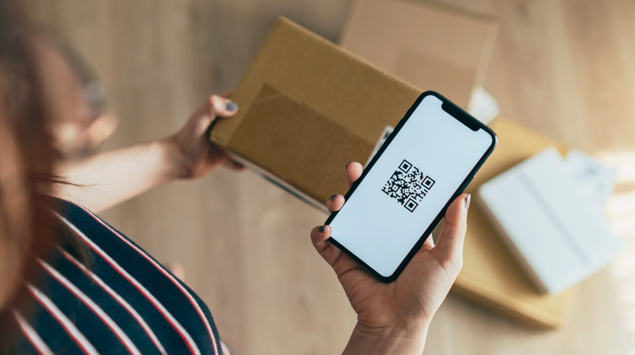Street vendor in bustling market holding large printed USDC QR code as customer scans with phone for offline stablecoin payment
